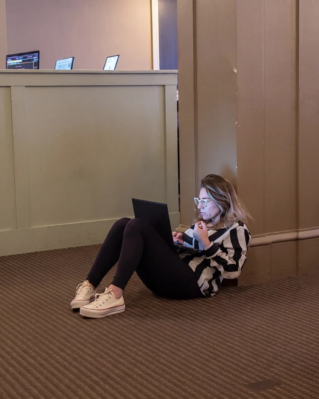 Student sitting on the floor working on a laptop between classes